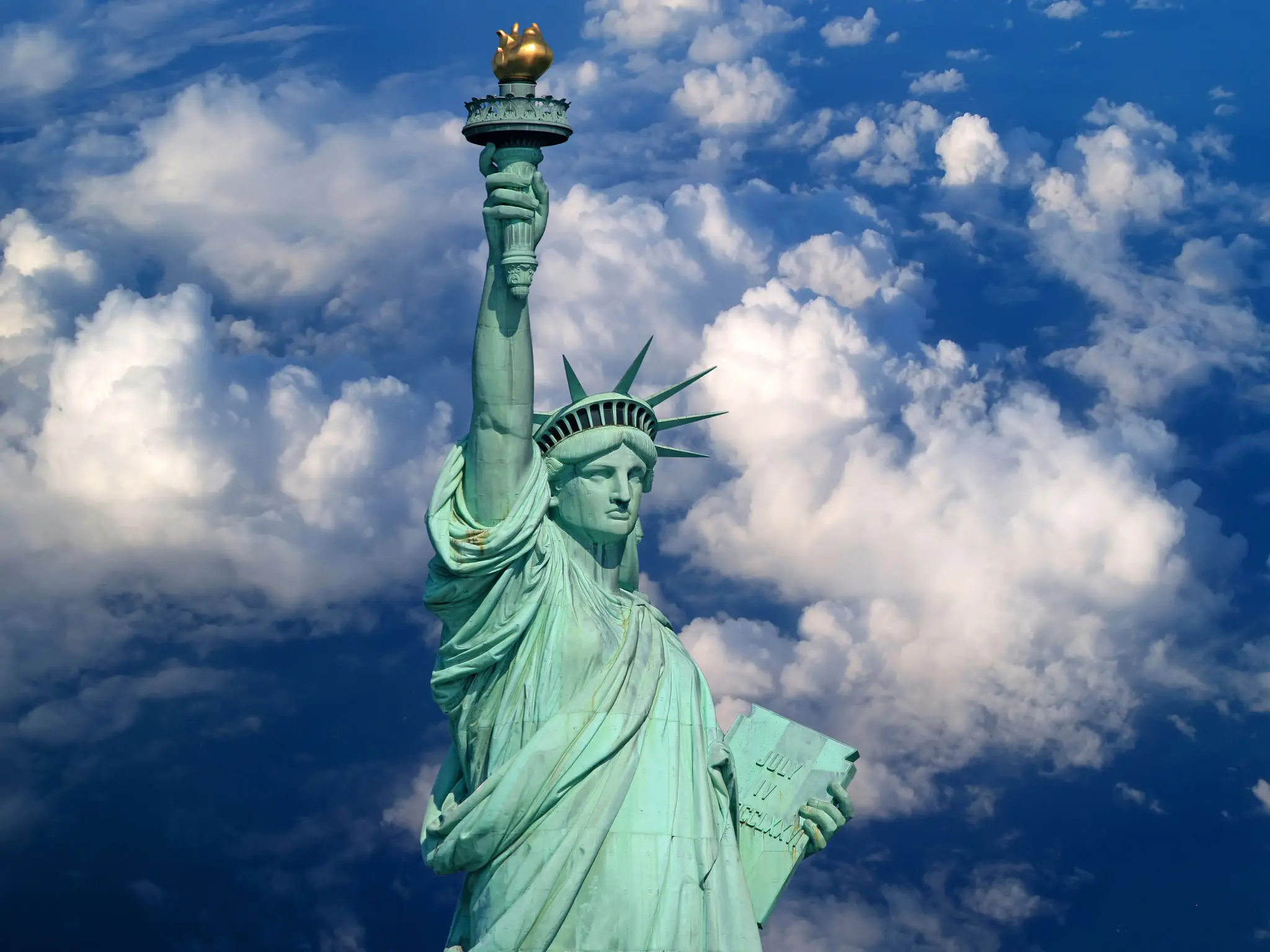 Statue of Liberty against a partly cloudy blue sky.